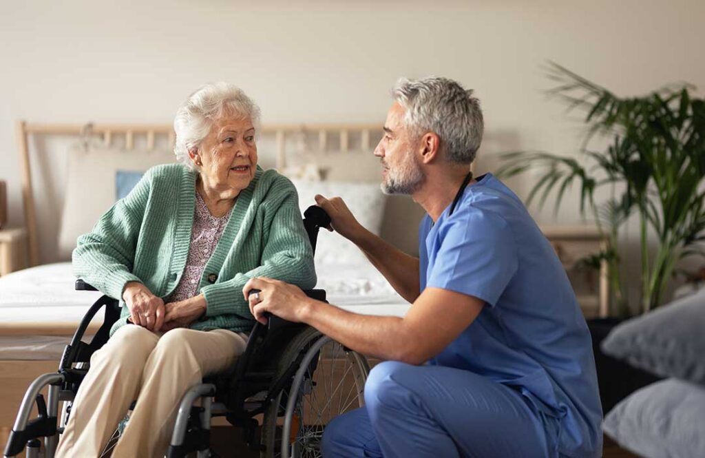 Family member sits beside an older adult during a small assisted living music activity.