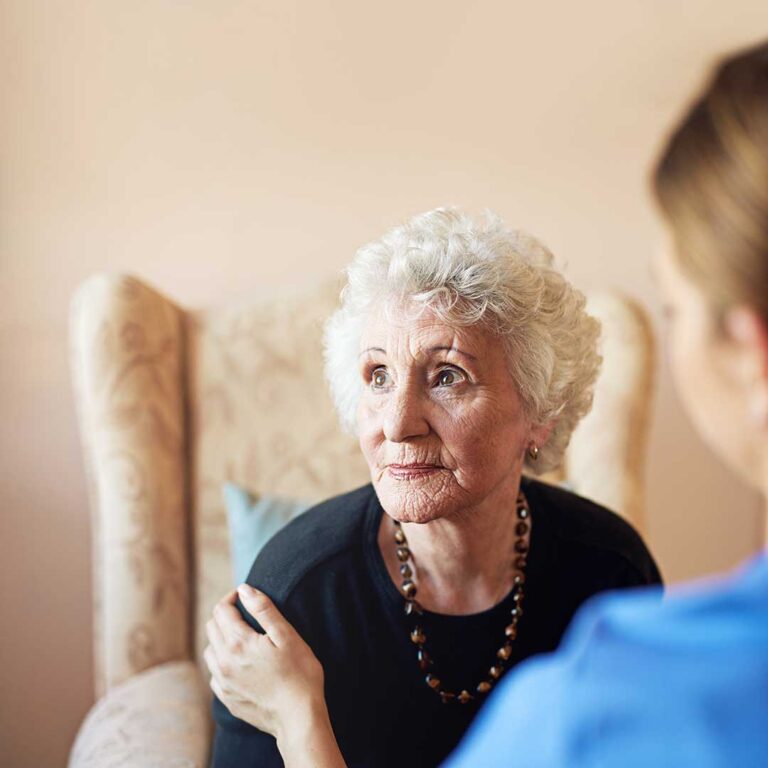 Caregiver reviews a personalized care plan with an older resident at a dining table.
